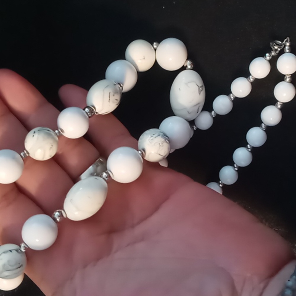 White with a marbeling black beaded necklace .